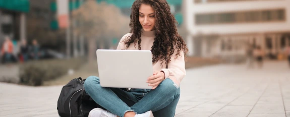 person sitting outdoors with a laptop
